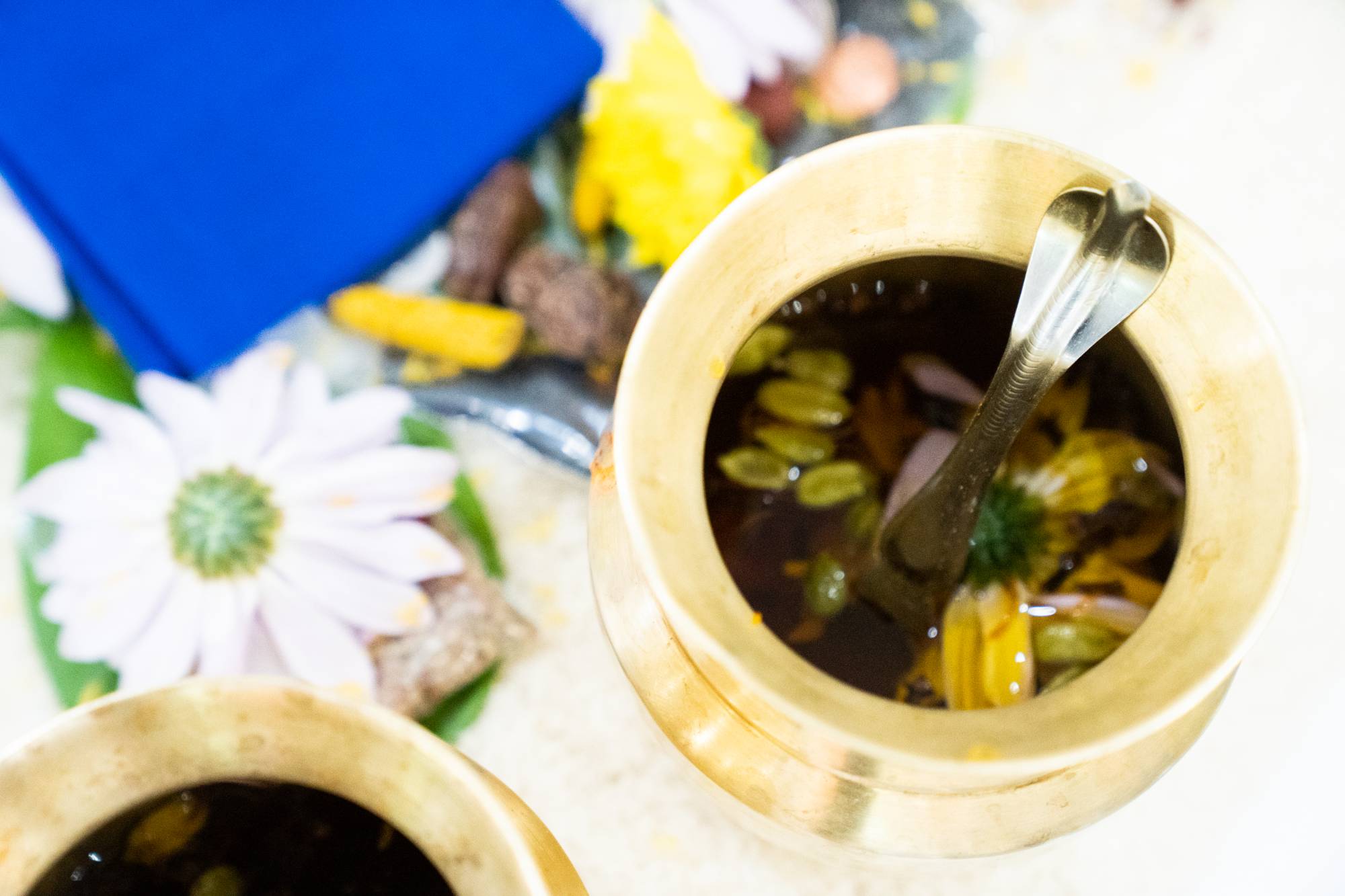 An image of flowers and medicinal beverage in a copper cup